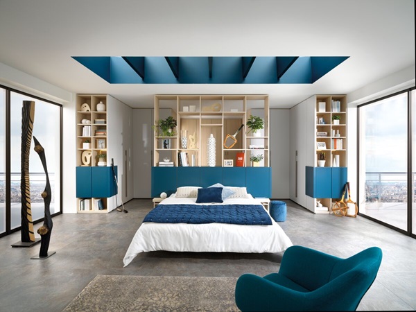 Schräge Ansicht von Bett, Regalsystem und Ankleide des Schlafzimmers in Arcos Melamin, Holzdekor Magnus und Weißton Celest.