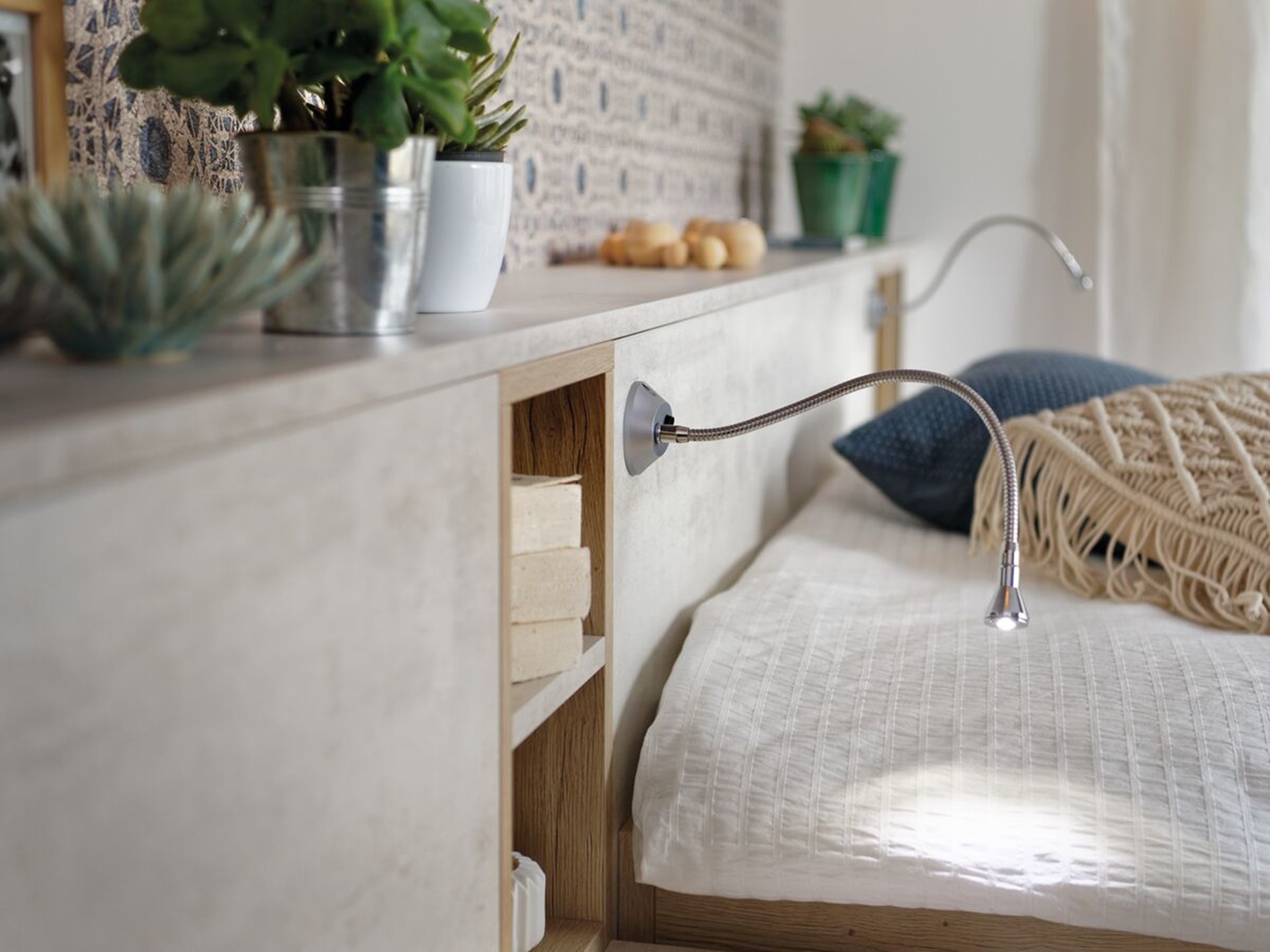 Vue de détail d'ambiance du rangement Arcos melaminé en coloris beige clair, cadrée sur le meuble tête de lit et les lampes intégrées