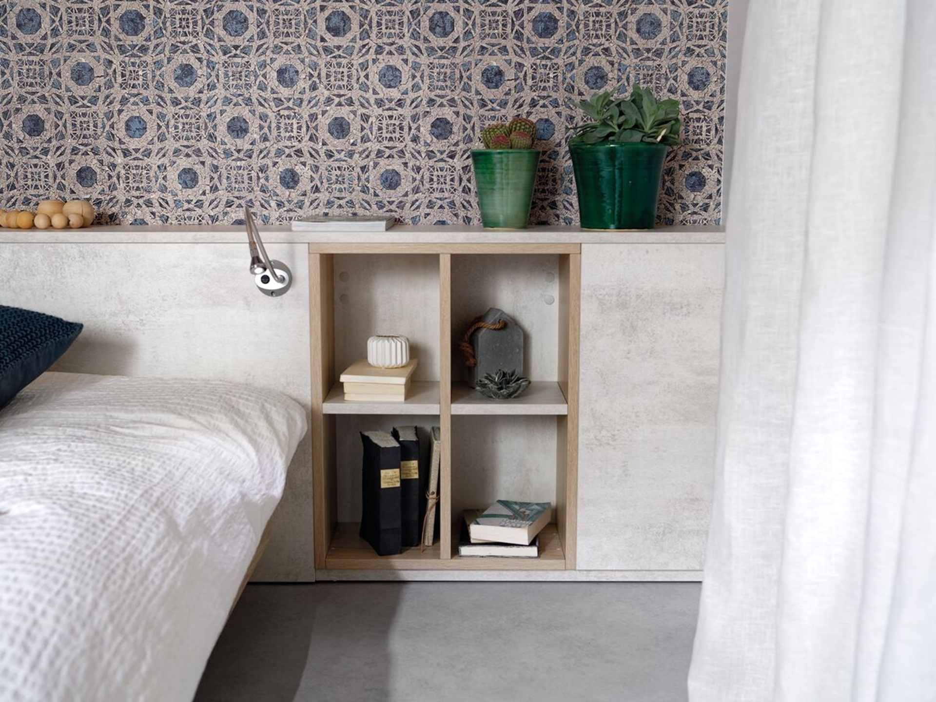 Vue de détail d'ambiance du rangement Arcos melaminé en coloris beige clair, cadrée sur la niche du meuble tête de lit