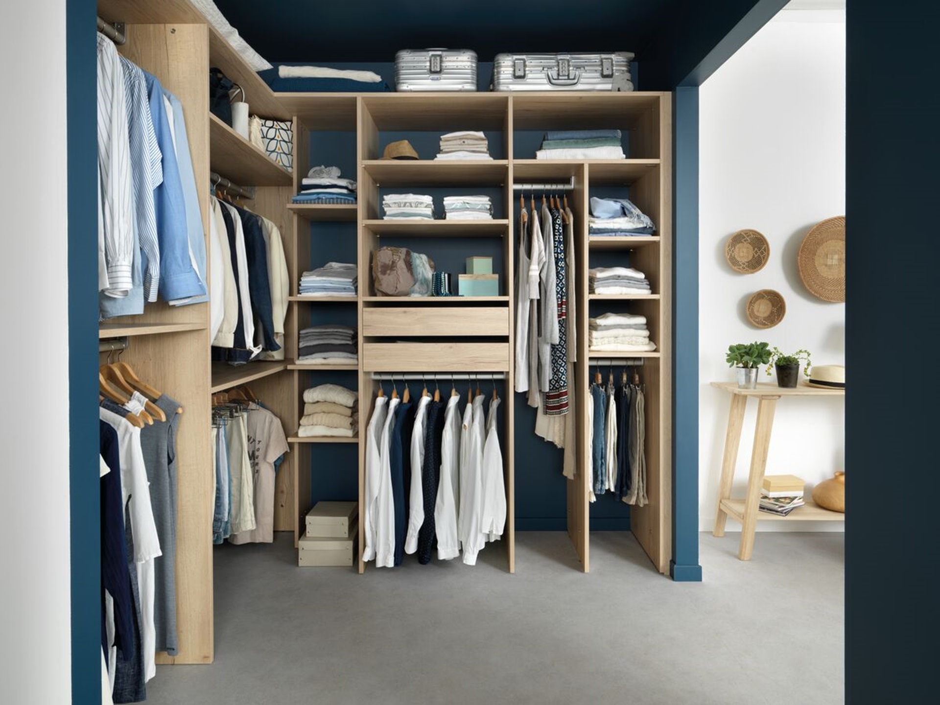 Vue en profondeur du dressing Arcos melaminé en coloris beige clair, une table d'appoint en arrière plan