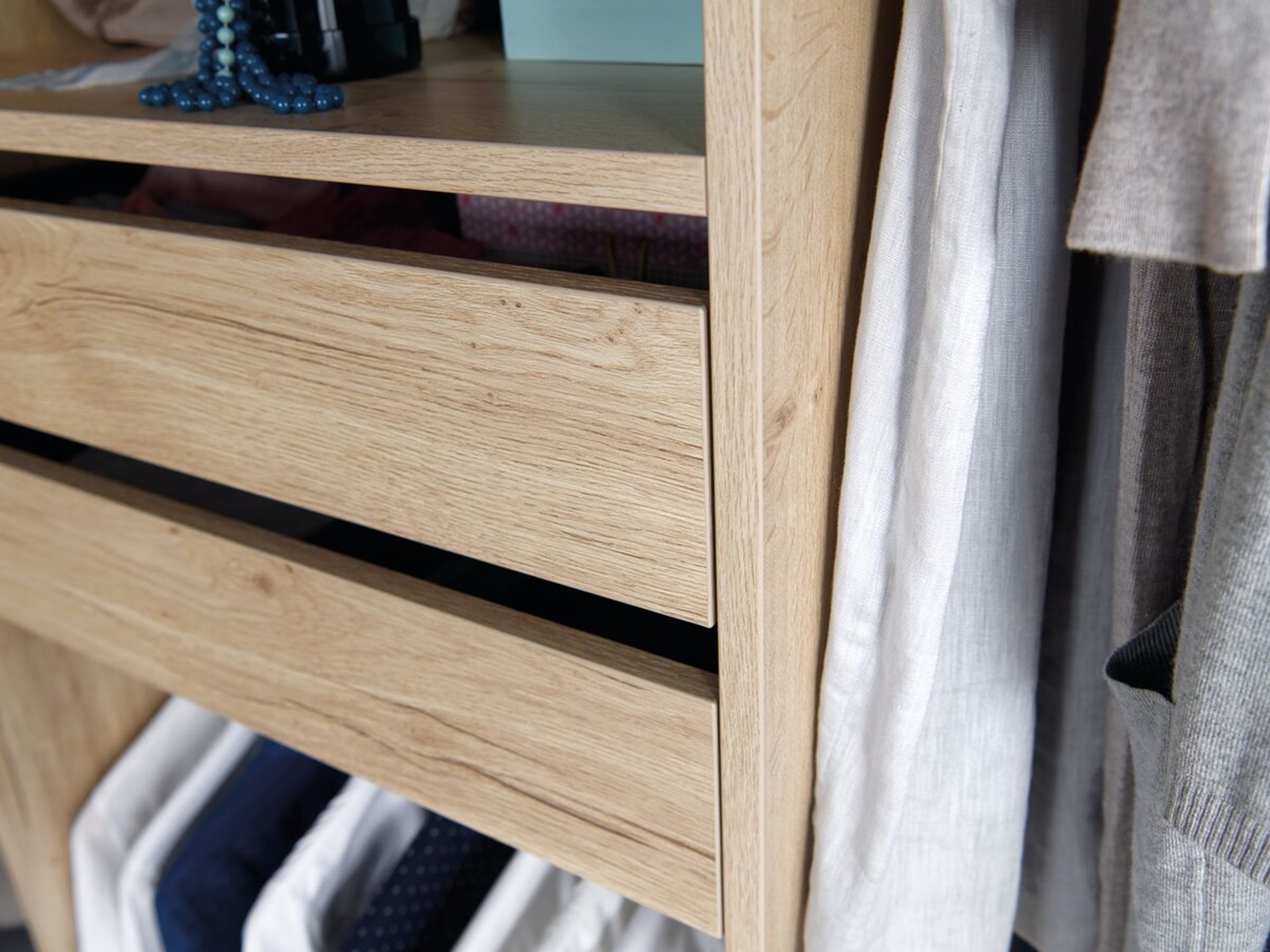 Vue de détail d'ambiance du dressing Arcos melaminé en coloris beige clair, cadrée sur les tiroirs du dressing
